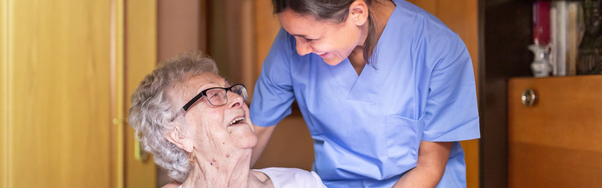 aide and senior woman looking at each other and smiling